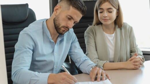 homme qui signe un contrat en étant assis à côté d'une femme